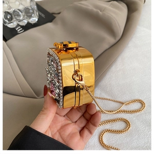 Macro detail of gold mirrored evening bag with crystals and bee clasp ornament