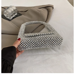 Detail of handcrafted silver beaded handbag featuring glossy metallic woven beads and flap