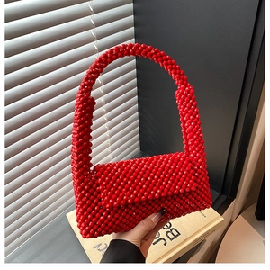 Detail of red acrylic beaded woven handbag featuring a flap closure and handmade texture