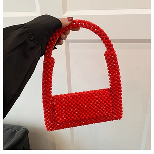 Close-up of vibrant red acrylic beads and handcrafted weaving on the shoulder bag