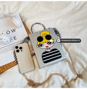 Silver box clutch bag with cartoon girl print compared to iPhone 12 for size