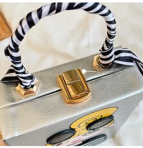 Silver evening box bag featuring cartoon design and gold clasp with striped silk handle