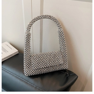 Detail of silver beaded shoulder bag with textured acrylic beads on a black leather seat