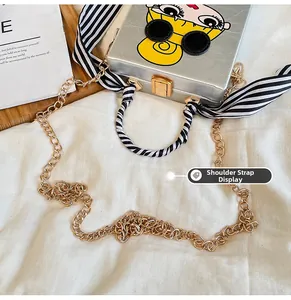 Detail of silver box clutch with girl graphic, scarf handle and gold chain strap