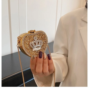 Close-up of gold heart-shaped mini evening bag with rhinestones and crown emblem