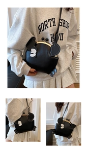 Macro detail of quirky black crab cross-body bag featuring metal clasp and leather texture