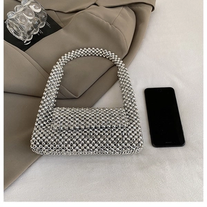 Close-up of silver beaded handbag with metallic beads and rectangular flap structure