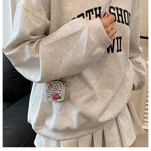 Detail of a mini rhinestone crossbody bag with a red crystal lip pattern and chain