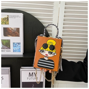 Detail of orange crossbody box bag featuring cartoon girl print and scarf-wrapped handle