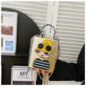 Detail of gold box bag with cartoon girl illustration and striped silk scarf handle