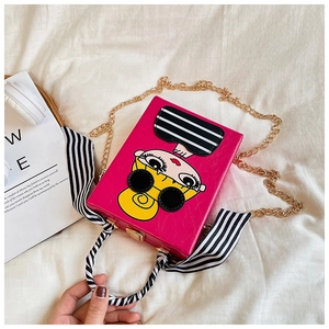 Top view of a bright rose red box bag with cartoon print and black-and-white scarf handle