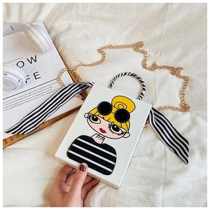 Detail of white cross-body box bag featuring cartoon portrait and golden chain strap