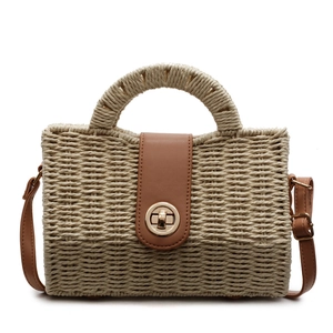 Fashionable woven straw handbag with brown leather flap and circular metal lock closure