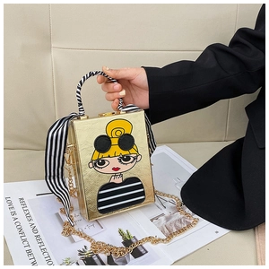 Detailed view of gold box bag featuring cartoon girl print and ribbon handle decoration