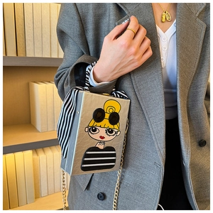 Detail of silver book-shaped clutch with cartoon girl print and striped scarf handle