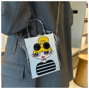Detail of silver box clutch bag featuring cartoon girl motif and striped ribbon decor