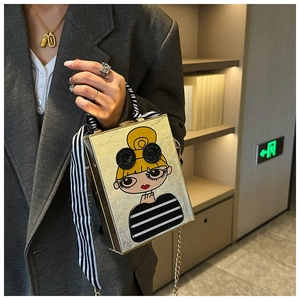 Detail of gold box bag featuring a cartoon girl print and striped scarf wrapped handle