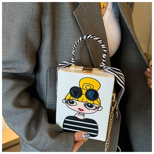 Detailed shot of white box clutch bag with cartoon girl illustration and silk scarf handle