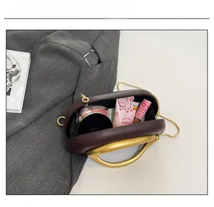 Internal capacity of the clutch bag showing cosmetics and a large gold ring handle