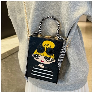 Close-up of black crossbody box bag with cartoon girl print and silk scarf on handle