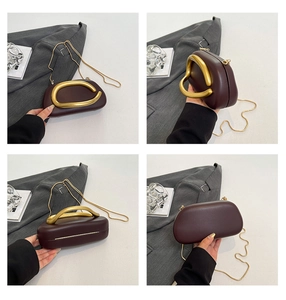 Detail view showing the burgundy leather shell bag with unique gold metallic ring handle
