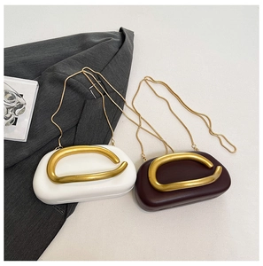 Close-up of minimalist pill-shaped crossbody bags with gold C-handle and metal chain