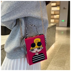 Detail of fuchsia box bag with cartoon girl illustration and gold chain on a model
