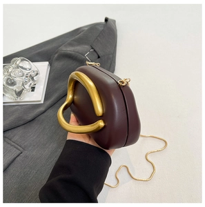 Detail of burgundy mini shell bag with chunky gold metal handle and chain strap