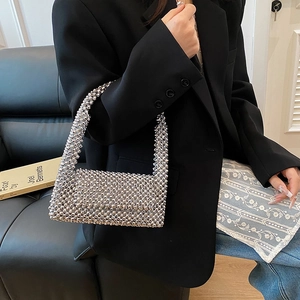 Silver beaded top handle bag with metallic finish shown held by a model in lifestyle setting
