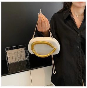 Detail of white oval shell bag with large gold metal hardware and slim chain strap