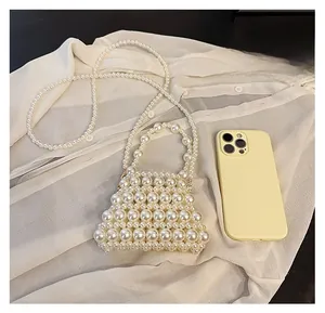 Mini pearl woven bag with crossbody strap shown next to a smartphone for scale