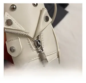Detailed view of silver metal zippers and round rivets on white leather mini bag