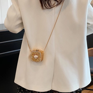 Golden square crossbody bag with rhinestones and fox head detail on white suit background