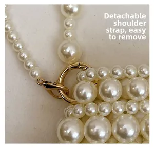 Close-up of handmade pearl bag showing detachable golden lobster clasp and strap details