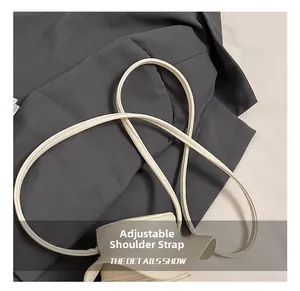 Detail showing adjustable slim leather shoulder strap on a beige mini crossbody bag