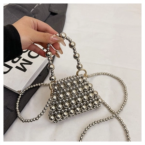 Détail d'un mini sac perlé argenté au fini métallique et longue bandoulière
