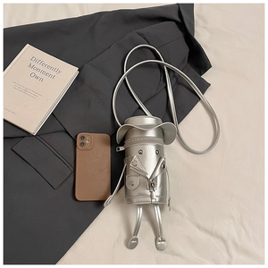 Detailed view of silver robot-shaped crossbody bag styled with trendy clothing accessories