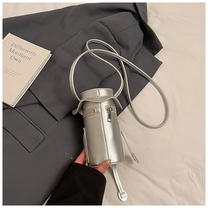 Detail of a silver cylindrical mini crossbody bag with a metallic finish and zip top