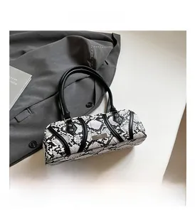 Close-up of stylish snakeskin pattern boston handbag with metallic plate details