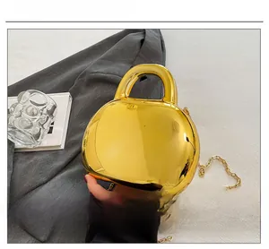 Detail of glossy gold acrylic shell bag with metallic mirror finish and chain strap