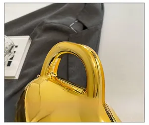 Detail of the golden acrylic shell bag showing U-shaped handle and metal clasp