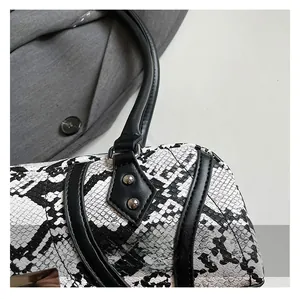 Close-up of the black and white snake skin texture with silver rivets on the handbag handle