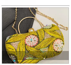 Detail of yellow vintage evening bag with floral sequins, gold handle, and pearl clasp