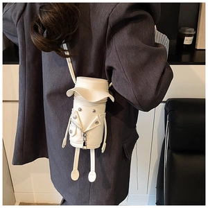 Detail of creative cartoon jacket-shaped crossbody bag worn over a grey blazer
