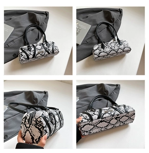Detail of snake skin pattern barrel bag featuring double handles and metal hardware