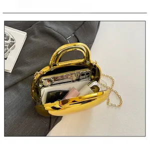 Internal capacity of gold mirror acrylic shell bag showing phone and lipstick space