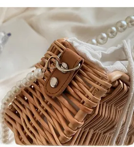 Detail of woven straw bag showing pearl chain strap and silver metal hardware hook
