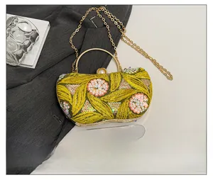Detail of yellow evening clutch with gold embroidery and a phone for size reference