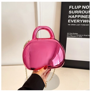 Detail of glossy fuchsia acrylic shell bag with metallic mirror finish and gold chain