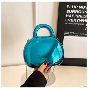 Detail of bright blue mirror finish shell bag with gold chain strap and integrated handle